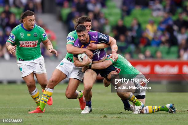 Jesse Bromwich of the Storm is tackled by Joseph Tapine and Adam Elliott of the Storm during the round 18 NRL match between the Melbourne Storm and...