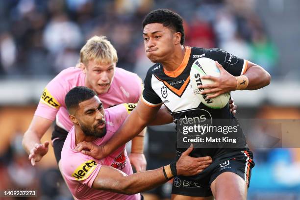 Junior Tupou of the Tigersputs a fend on Robert Jennings of the Panthers during the round 18 NRL match between the Wests Tigers and the Penrith...