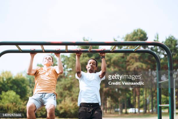 friends working out together outdoor - boys in pullups stockfoto's en -beelden
