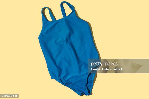 green female swimsuit with hard shadow on yellow background. concept of heat, summer, beach, pool, swimming, swimming and sunlight. - badkläder bildbanksfoton och bilder