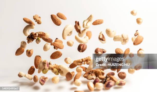 different nuts falling, walnut almonds hazelnuts pistachios cashews - amendoim noz - fotografias e filmes do acervo