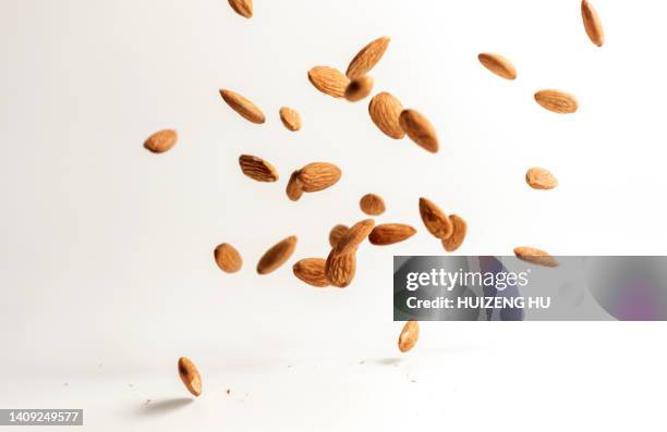 flying almond nuts on white background - mandel stock-fotos und bilder