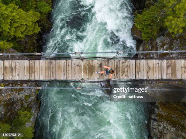 top down view of a woman running over a suspension bridge over a river - whistler british columbia stock pictures, royalty-free photos & images