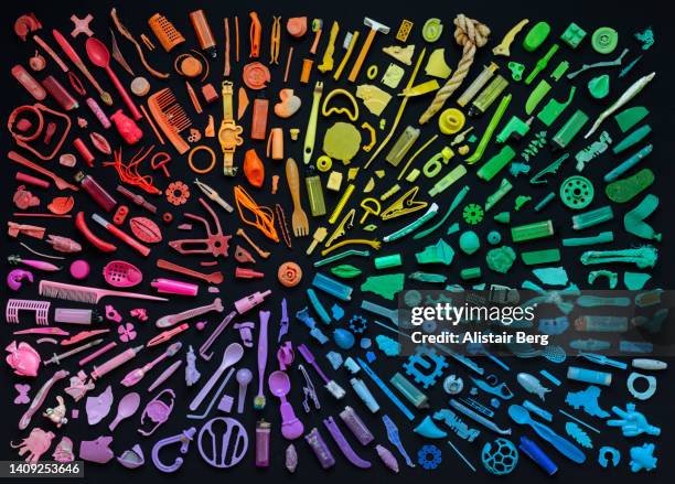 rainbow coloured arrangement of plastic items washed up on the beach - kunstprodukten stock-fotos und bilder