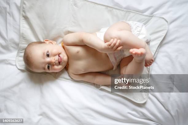 niña acostada en la cama mientras usa solo pañal - one baby girl only fotografías e imágenes de stock