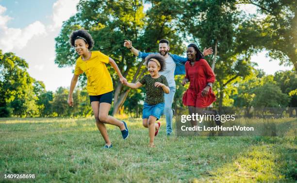 playful multiracial family in the park - tag 7 stock pictures, royalty-free photos & images