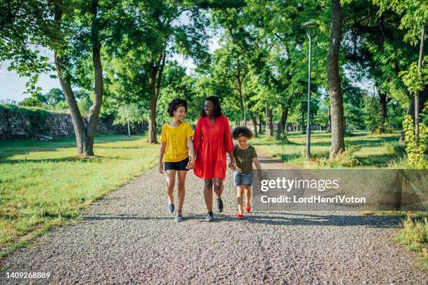 mother with her daughters walking in public park - lane sisters stockfoto's en -beelden