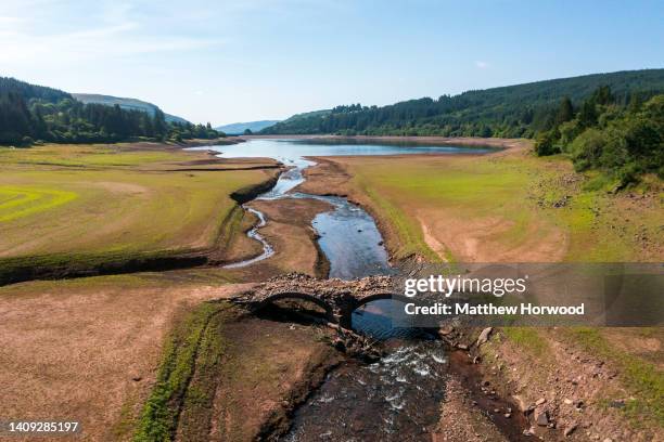 An aerial view of an exposed bridge normally underwater at the Llwyn-on Reservoir, the largest of the three reservoirs in the Taf Fawr valley on July...