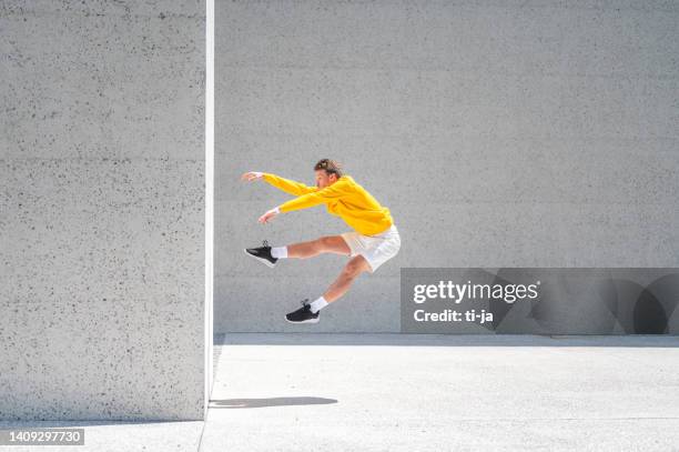 jeune homme sautant par le grand mur de béton à l’extérieur - the concrete wall photos et images de collection