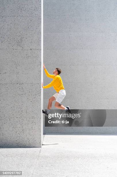 hombre adulto joven saltando sobre la pared de concreto - le parkour fotografías e imágenes de stock