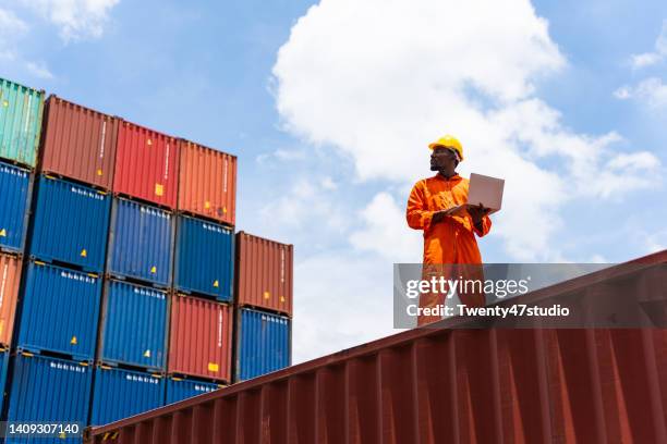 balck worker using a laptop working in the commercial dock - containers harbour stock pictures, royalty-free photos & images