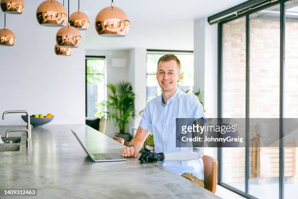 at-home portrait of early 30s man wearing prosthesis - bionic arm stock pictures, royalty-free photos & images