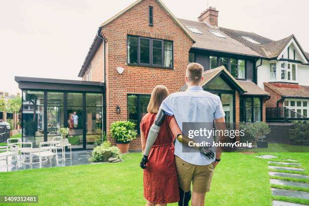 young couple wearing prostheses and admiring new home - bionic arm stock pictures, royalty-free photos & images