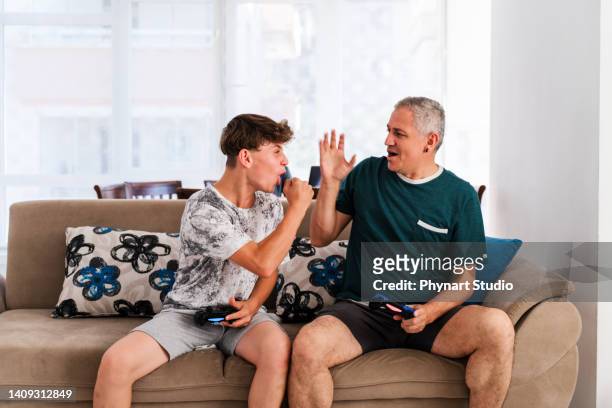 père et fils en compétition dans des jeux vidéo à la maison - father son challenge round two photos et images de collection