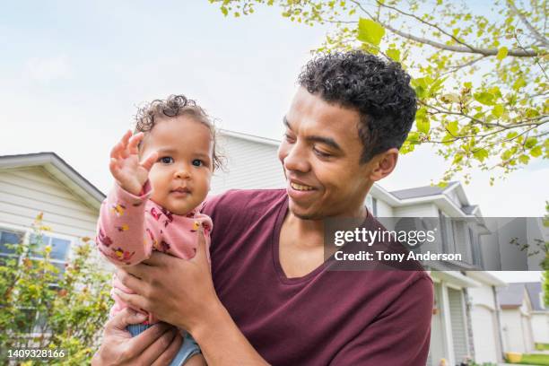 father holding baby daughter outside home - intergénero fotografías e imágenes de stock