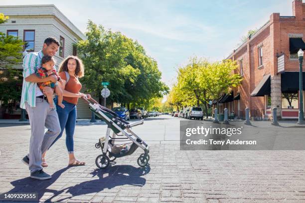 young family strolling with baby daughter on city street - stadsgata bildbanksfoton och bilder