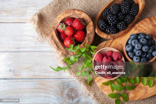 bunte beeren-sortiment auf rustikalem holztisch - summer fruits stock-fotos und bilder