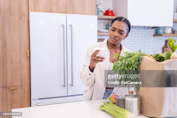 woman puzzled reviewing her grocery bill - adding machine tape stock pictures, royalty-free photos & images