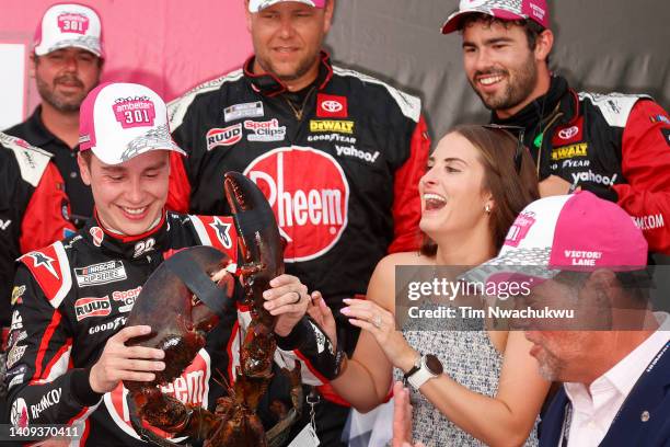 Christopher Bell, driver of the Rheem/WATTS Toyota, is presented Loudon the Lobster, as his wife wife Morgan Bell looks on in victory lane after...