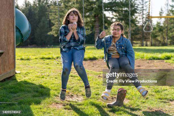 sisters playing on swing set with pet rabbits - backyard swing set stock pictures, royalty-free photos & images
