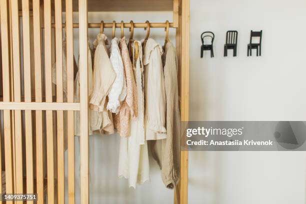 neatly hung clothes on hangers in wooden closet. - childrens closet stock pictures, royalty-free photos & images