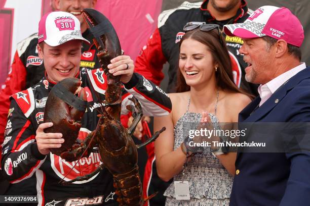 Christopher Bell, driver of the Rheem/WATTS Toyota, is presented Loudon the Lobster, as his wife, Morgan Bell looks on in victory lane after winning...