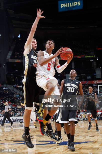 Nick Faust of the Maryland Terrapins drives for a shot attempt against Carson Desrosiers and Travis McKie of the Wake Forest Demon Deacons in the...