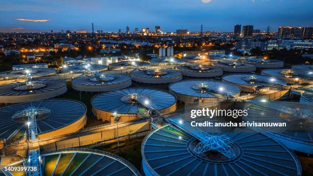 aerial view sewage treatment plant near downtown at night. - water treatment stock-fotos und bilder