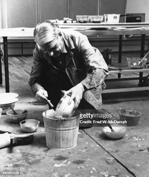 Dutch American artist Willem de Kooning mixes paints in a metal bucket of the floor of his loft studio, New York, New York, March 23, 1962.