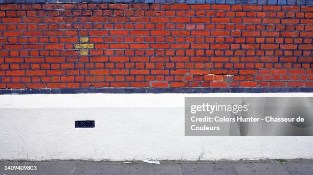 red and blue brick and white painted concrete wall with cement slab pavement in london, england, uk - grey brick wall stock pictures, royalty-free photos & images