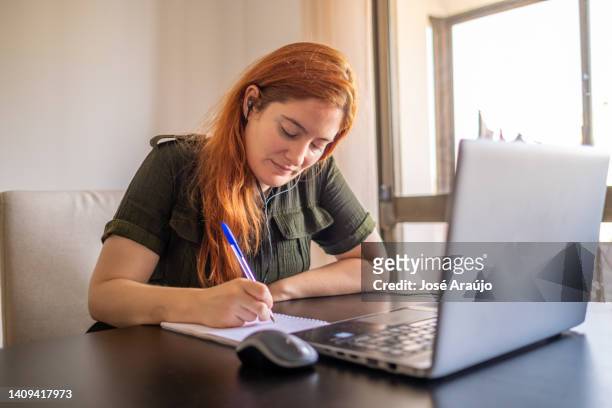 woman taking online courses with laptop and notebook and pen - pessoas notebook stock pictures, royalty-free photos & images