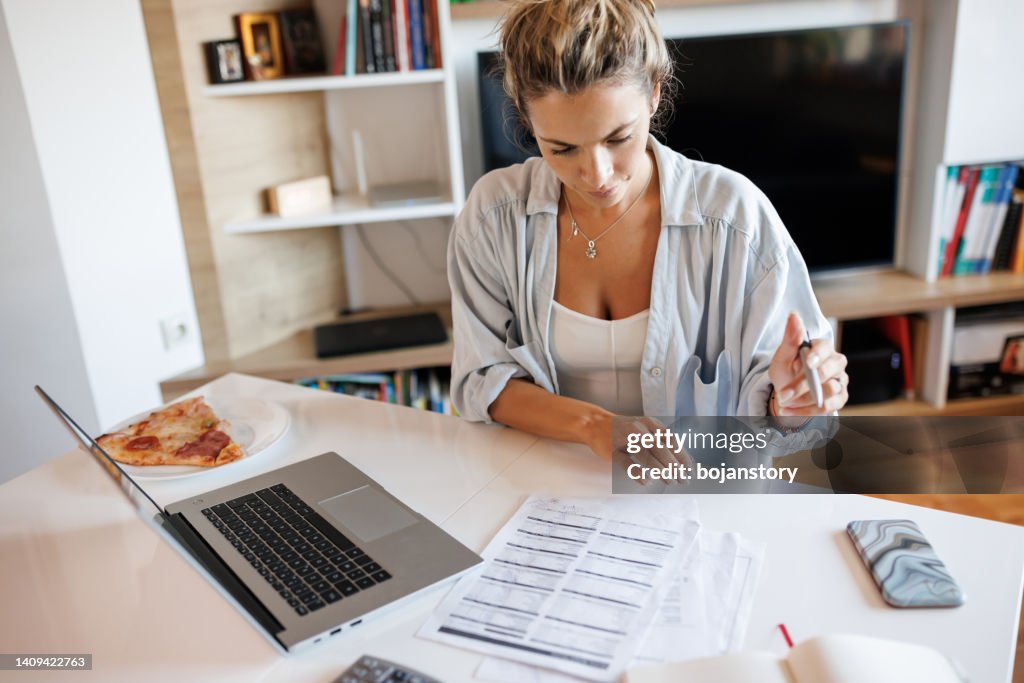 Young woman calculating expenses at home