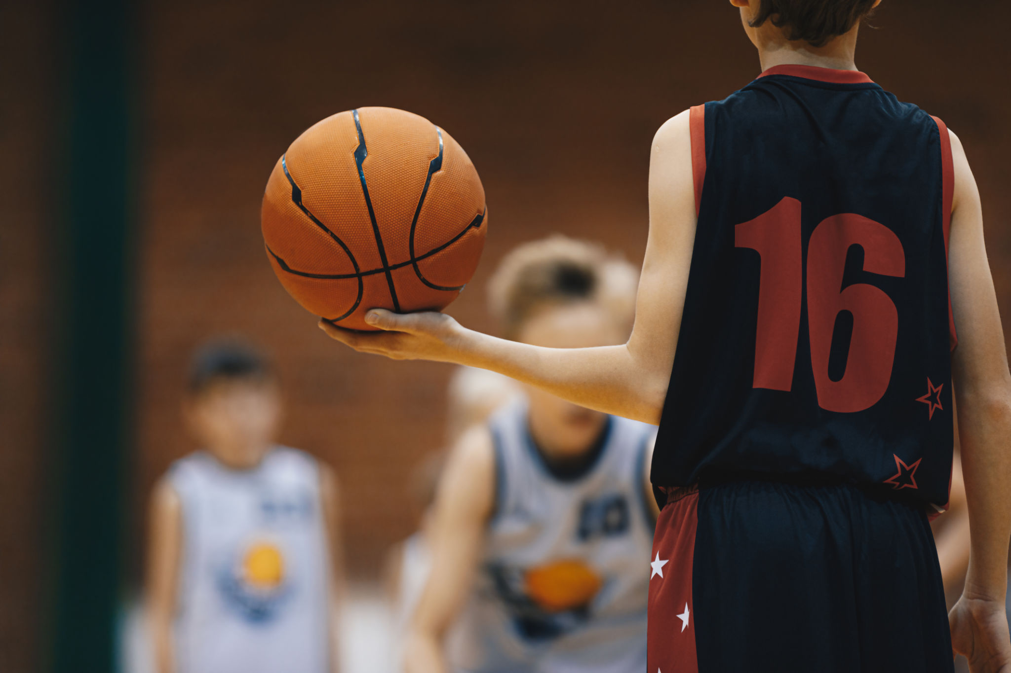 Young basketball player with classic ball. Junior level basketball player holding game ball. Basketball training session for kids Young basketball player with classic ball. Junior level basketball player holding game ball. Basketball training session for kids