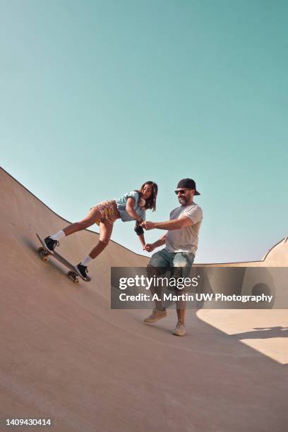 father teaching his daughter how to skate in a ramp. - skateboard park imagens e fotografias de stock