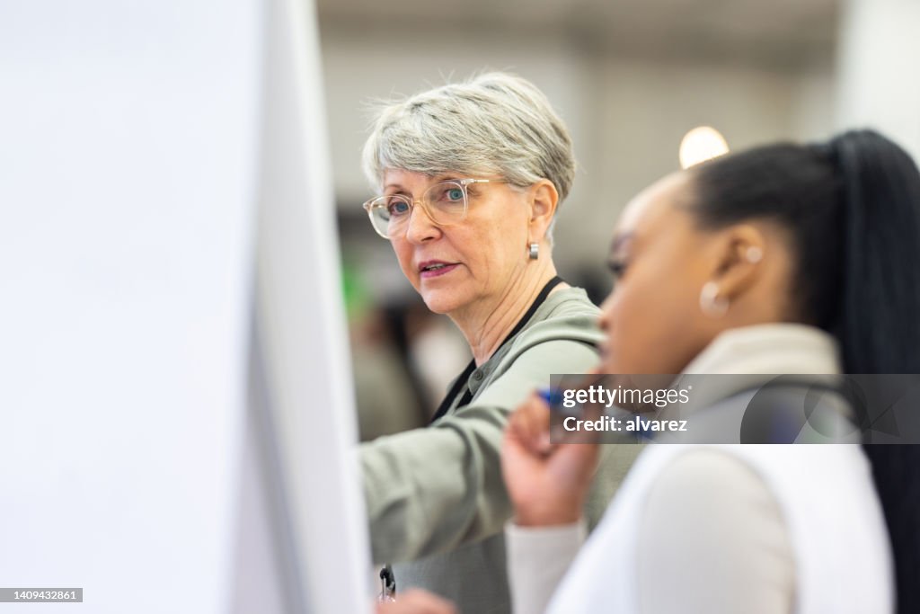 Diverse Geschäftsfrauen diskutieren im Workshop auf einem Flipchart