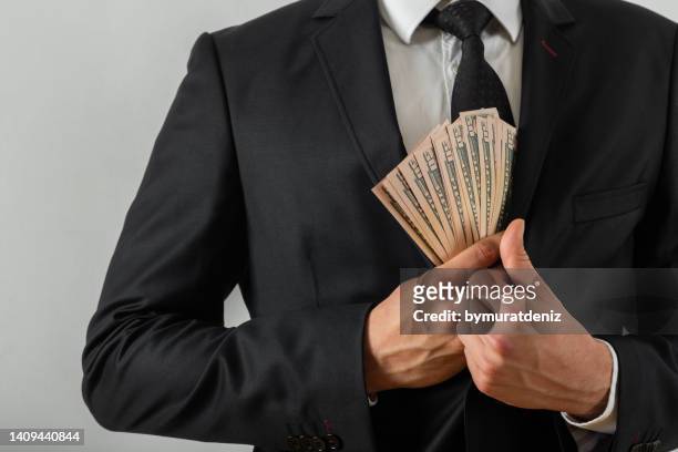 businessman putting us money into his suit pocket - money politics stock pictures, royalty-free photos & images