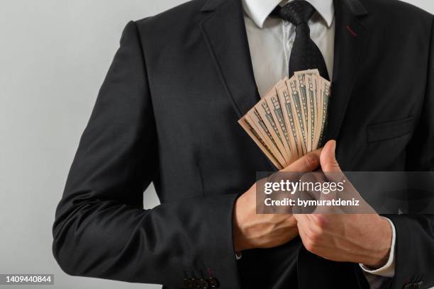 businessman putting us money into his suit pocket - bribery stock pictures, royalty-free photos & images