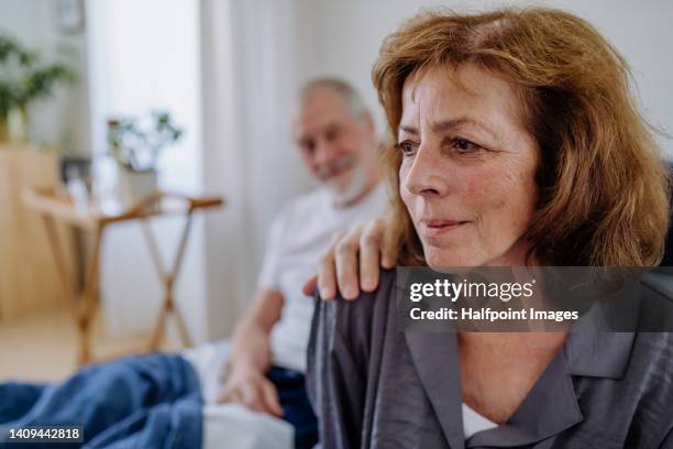 senior man consoling his wife in their bedroom. - husband stock pictures, royalty-free photos & images