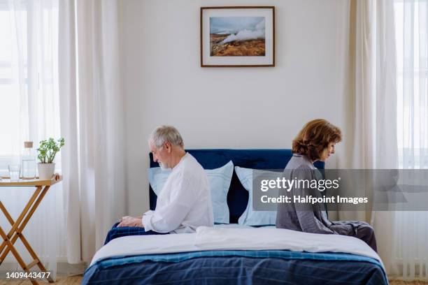 senior couple sitting in bed back to back. - divorcio fotografías e imágenes de stock