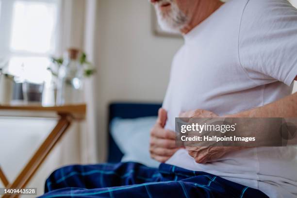 senior man with stomach pain sitting in bed. - gastric ulcer 個照片及圖片檔