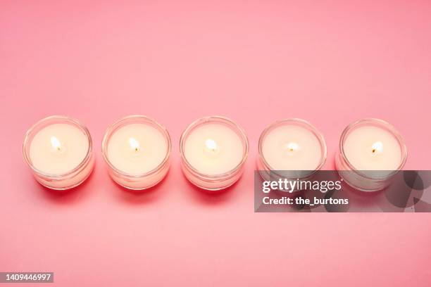 high angle view of tea light candles in a row on pink background - tealight stock pictures, royalty-free photos & images