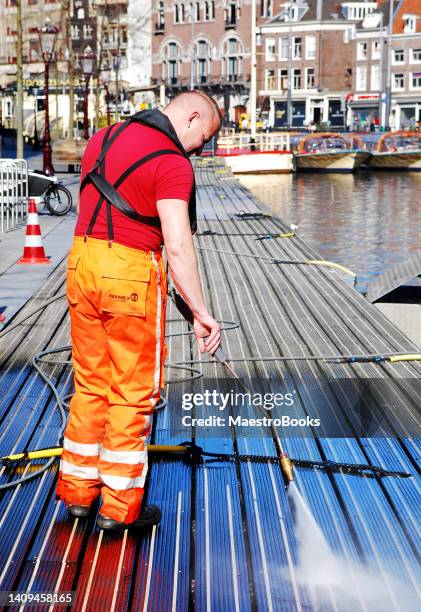 man removing chew gum with a high pressure washer at a canal pier. - duct cleaning stock pictures, royalty-free photos & images