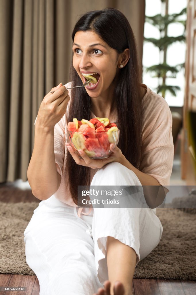 Happy woman eating slice of fresh fruit