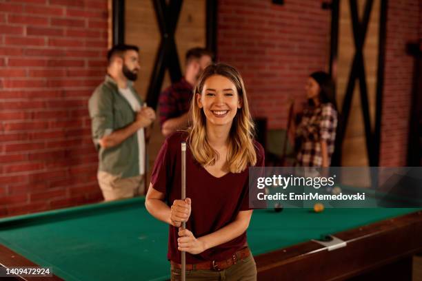 retrato de uma mulher nova com seus amigos que jogam o jogo da associação no fundo - snooker - fotografias e filmes do acervo