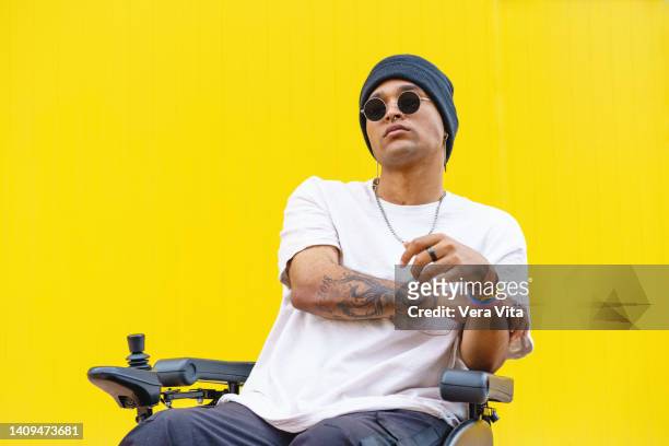 horizontal view of latin american man on wheelchair in yellow background. - man electric chair stock pictures, royalty-free photos & images