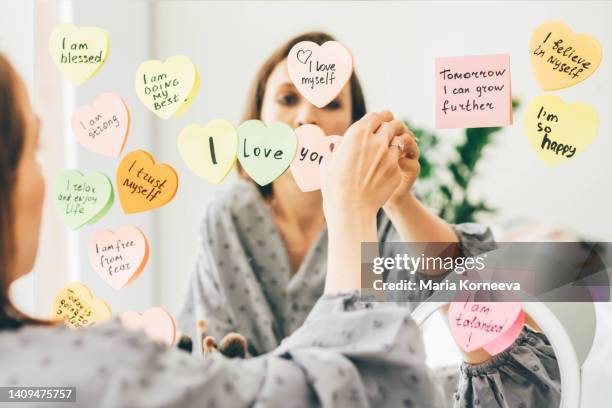 woman stick a sticker with affirmations on the mirror. - health motivational quotes stock pictures, royalty-free photos & images
