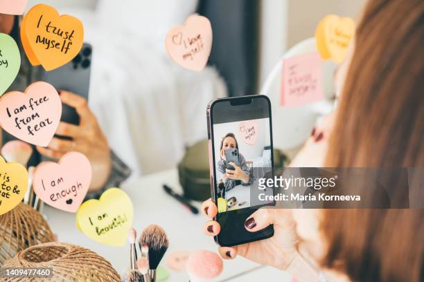 woman making video while stick a sticker with affirmations on the mirror. - health motivational quotes stock pictures, royalty-free photos & images