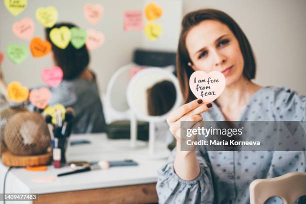 woman showing a sticker with affirmations near the mirror. - health motivational quotes stock pictures, royalty-free photos & images