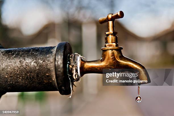 water falling from tap - gota agua fotografías e imágenes de stock