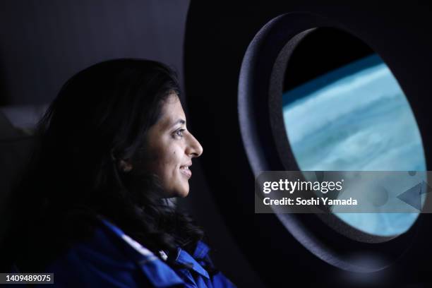 a commercial space traveler looking at the earth through window of the spaceship. - ruimtevaart voertuig stockfoto's en -beelden